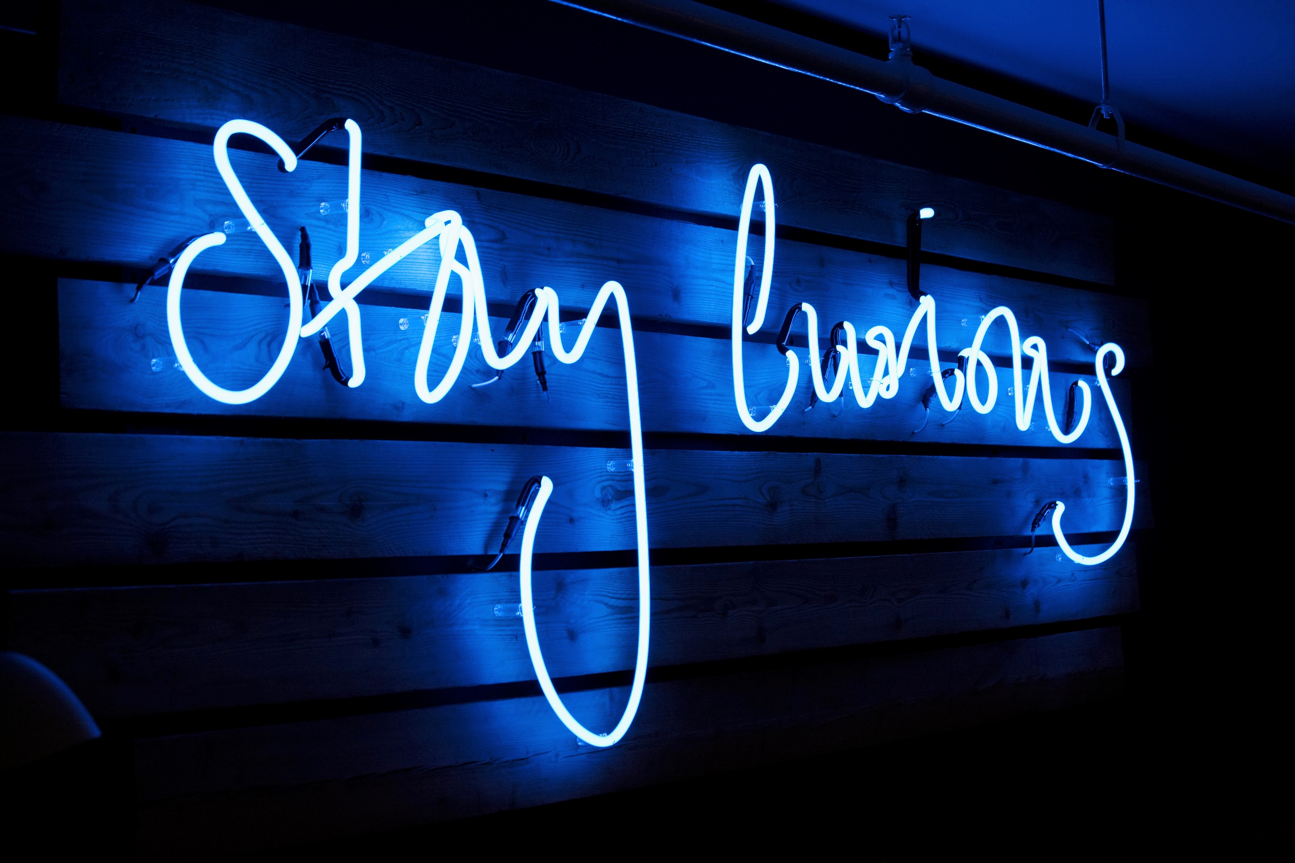 A neon sign on a hung wooden slat wall